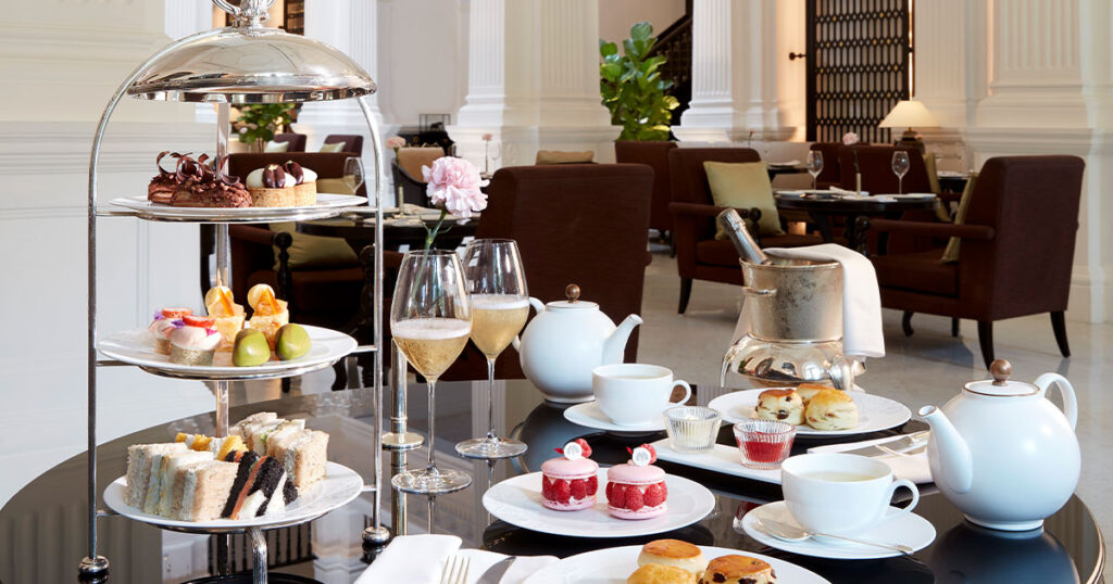 A table setting for Afternoon Tea at Raffles Hotel Singapore. It comes with a three tiered spread of delicate pastries, finger sandwiches and sweet treats.