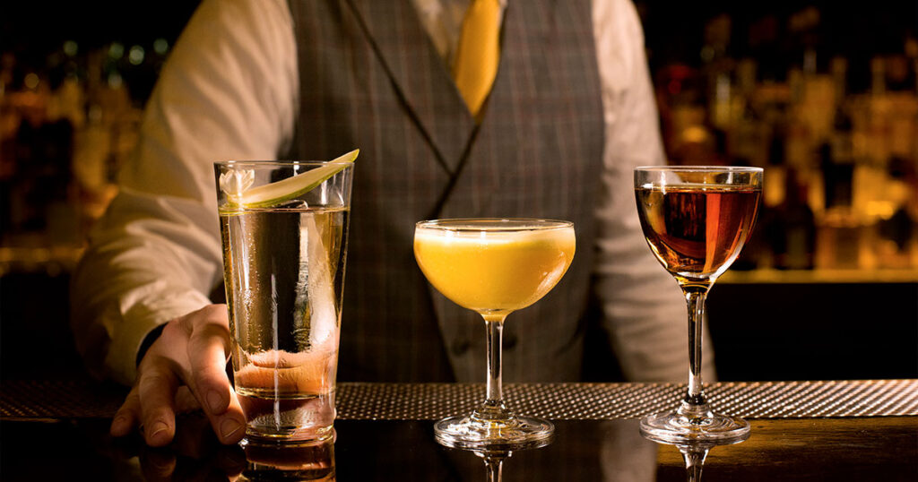 A bartender lining up three Cocktail Drinks in a row on the bar table in Singapore.