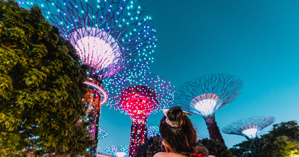 A lady in a red top watching the Light Show at Supertree Grove, Gardens by the Bay, Singapore.